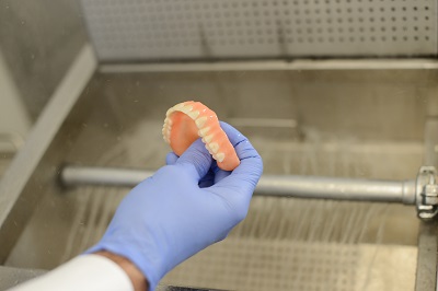 Denturist Holding a Complete Denture